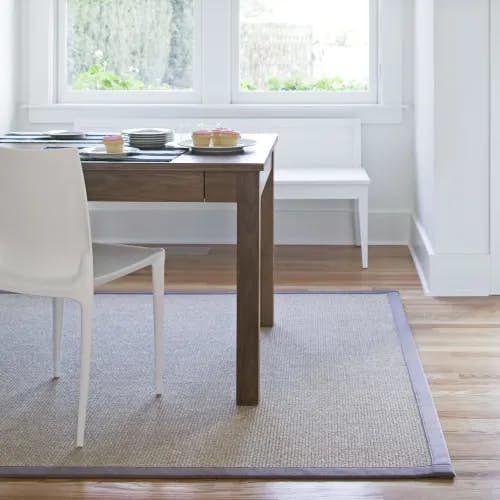 Orcas Evening Gray sisal area rug with cloth border in minimalist dining room